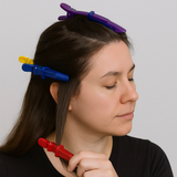 Woman sectioning her hair using colorful hair clips in red, blue, yellow, and purple.